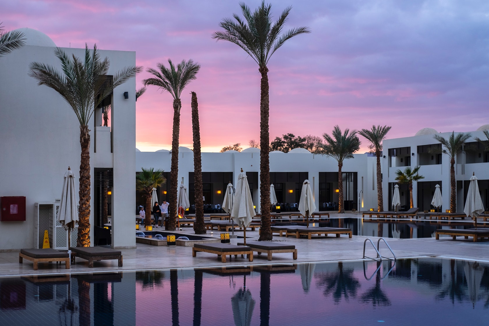 The image shows a luxurious hotel pool area at sunset, highlighting the importance of water softeners for hotels and restaurants to enhance guest experience and reduce maintenance costs