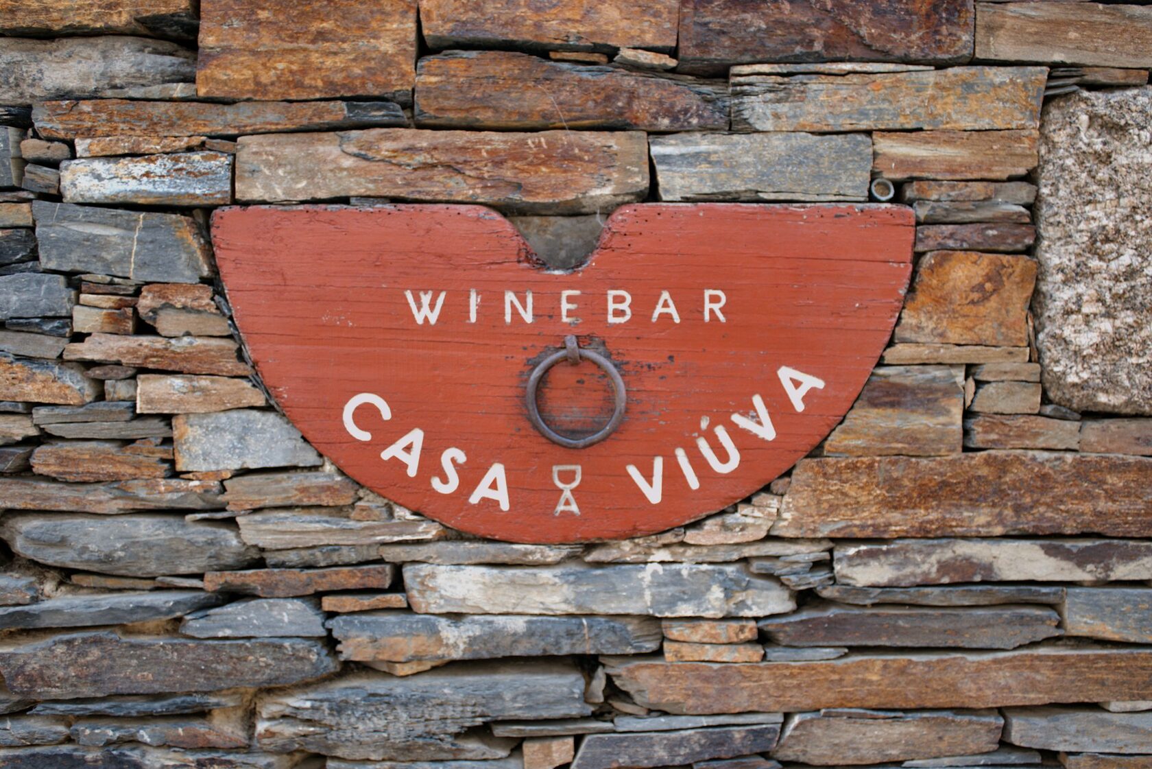 A glass of red wine resting on an old stone wall, vineyards rolling across the Chianti hills at golden hour