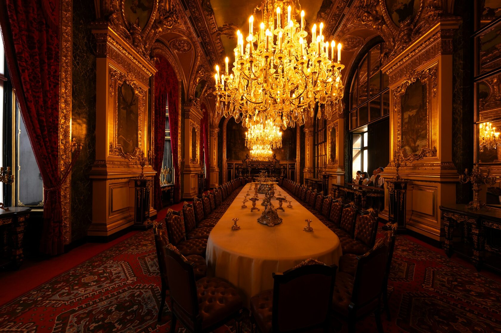 A grand medieval castle hall with long candlelit tables set for a feast, stone walls and tapestries, warm golden glow.
