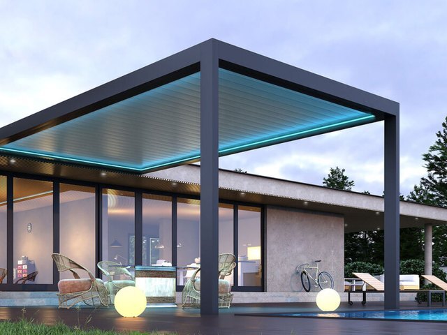ACURA Q25 louvered pergola with blue LED edge lighting beside a pool house
