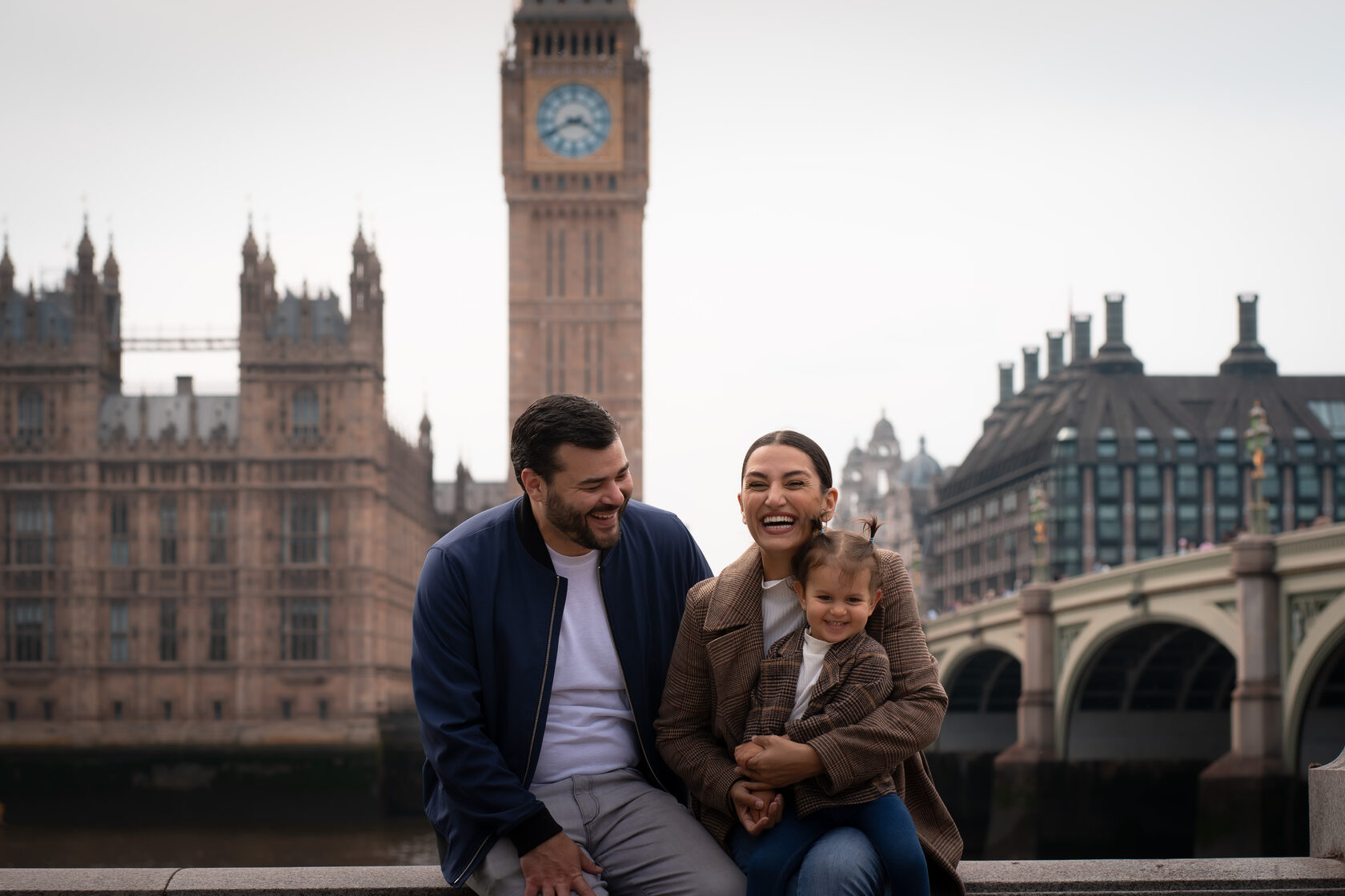 Parents smiling with their toddler beside the Thames