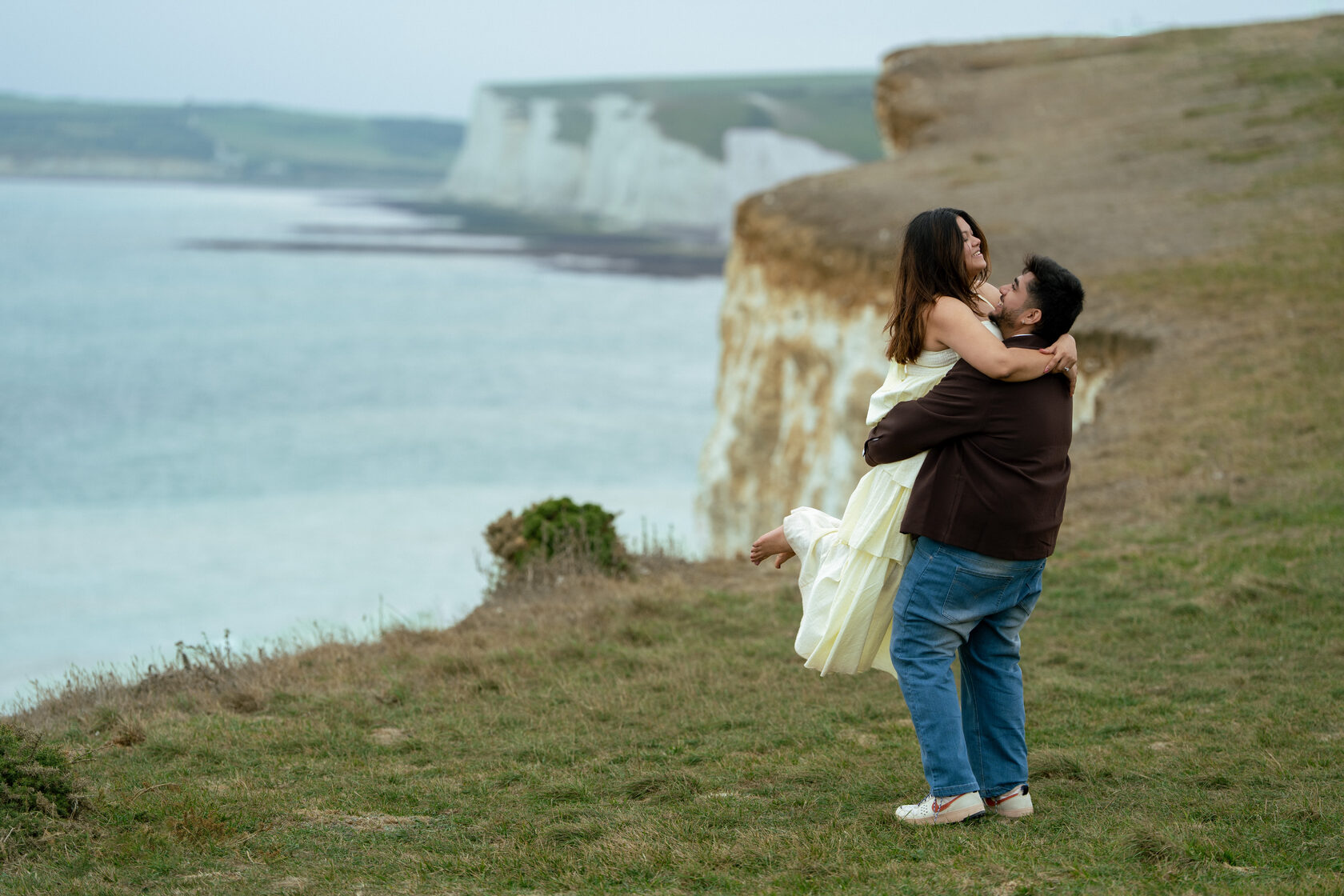 Wide portrait of a couple embracing with the Seven Sisters cliffs behind them
