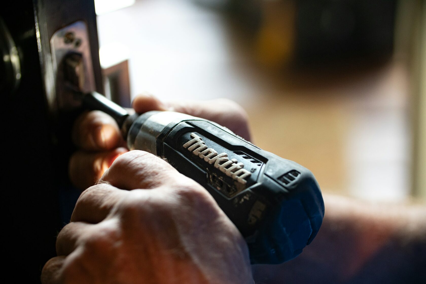 Technician using a drill to repair a roller shutter mechanism