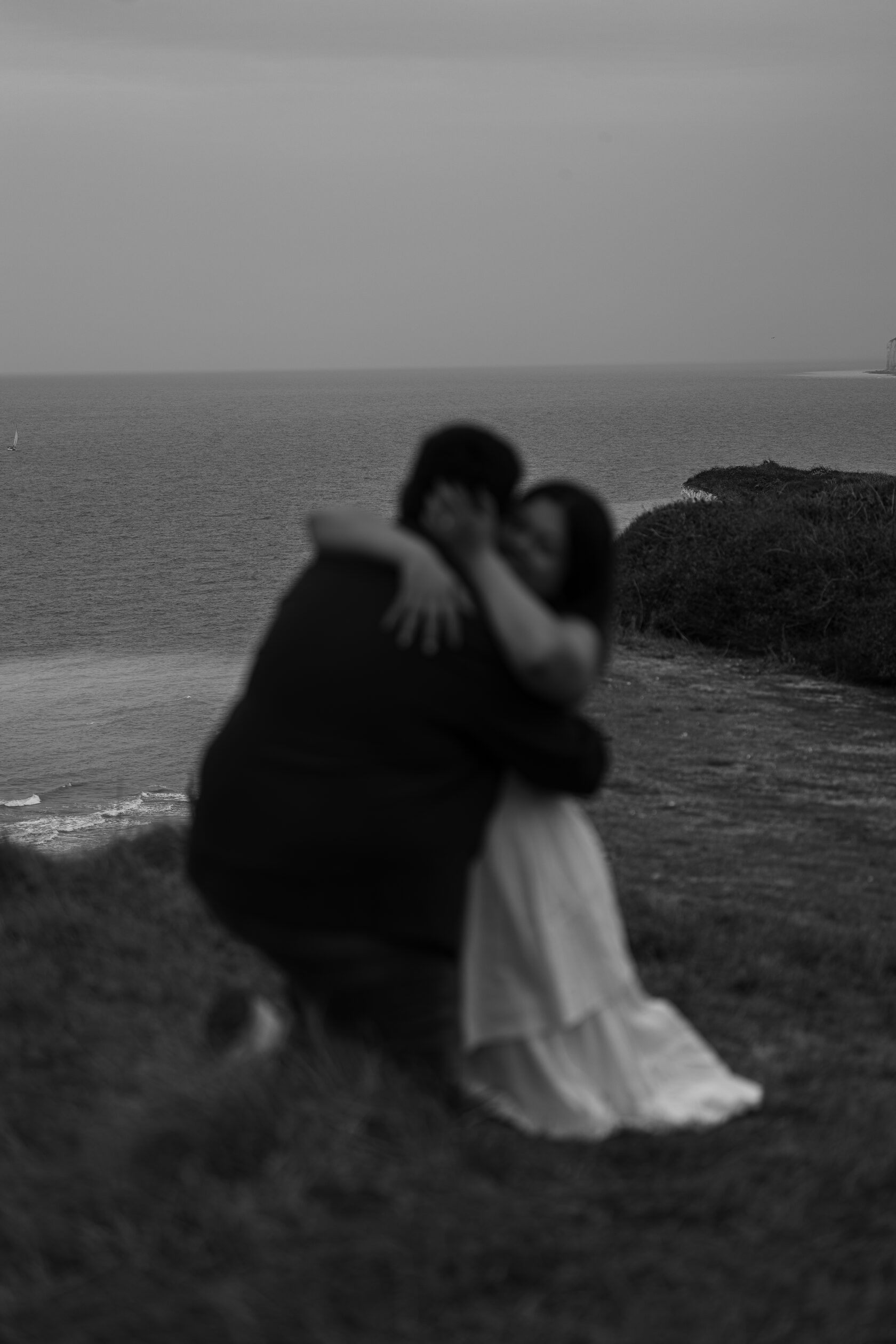 Black-and-white portrait of an embracing couple on the coast