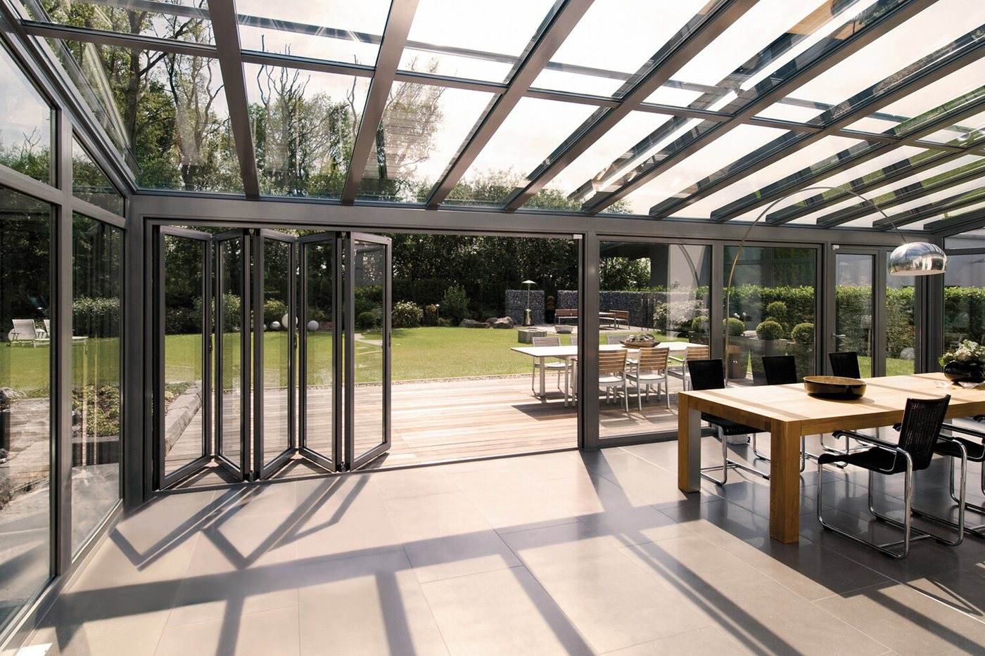 Folding glass doors and a glass roof opening a dining terrace to the garden