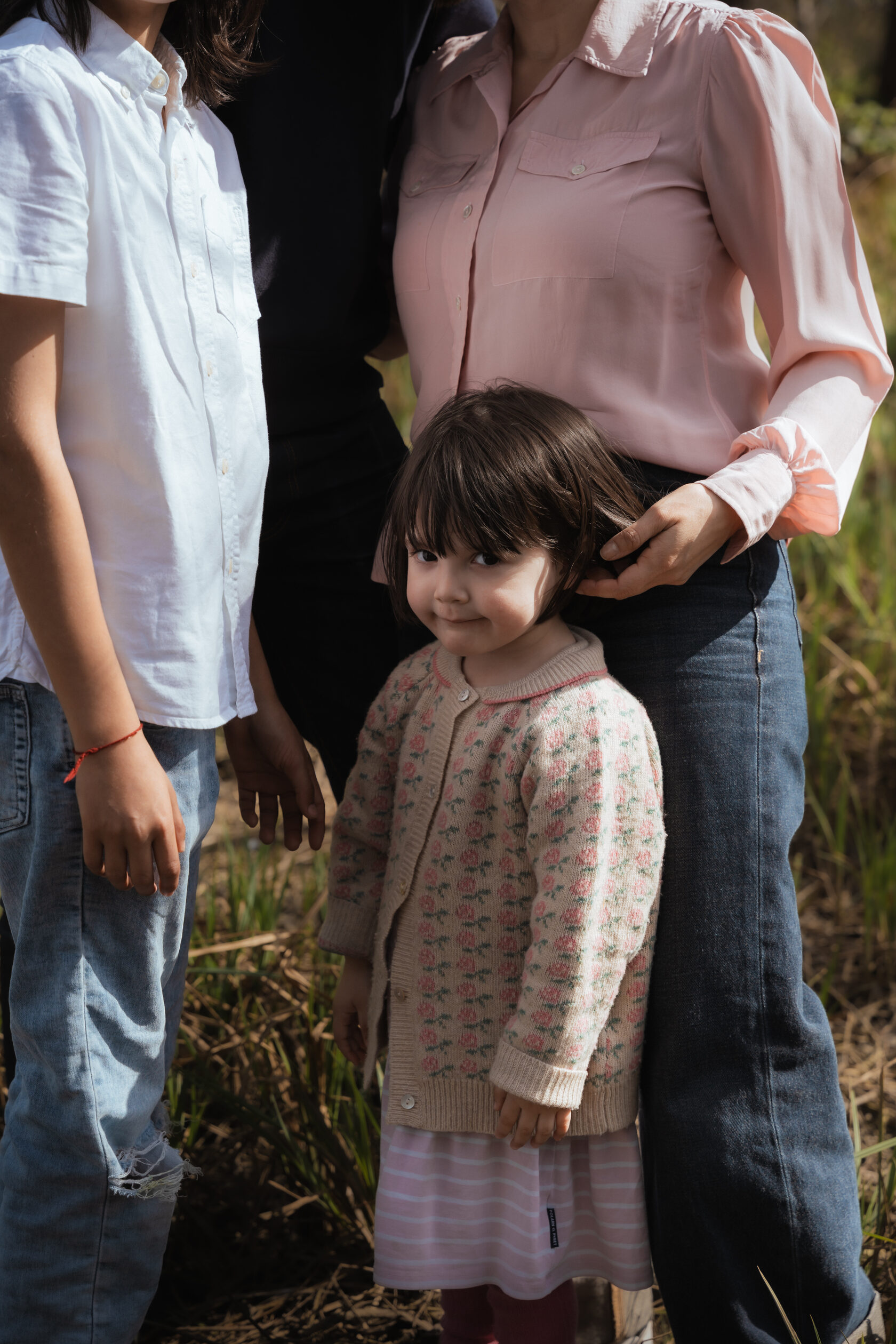 Close-up of a young child standing between parents