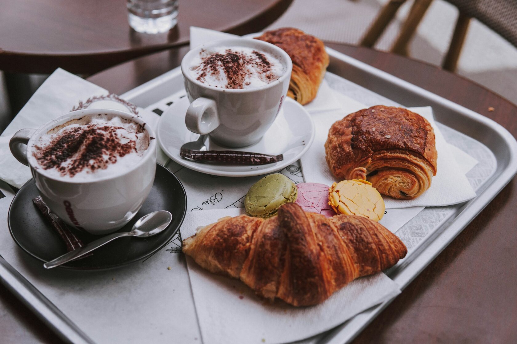 Golden croissants and a café crème on a small round marble table at a Paris sidewalk café