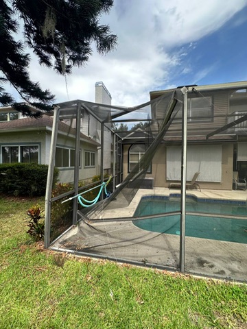 Pool cage corner with bent beams and torn screen after a storm in Orlando