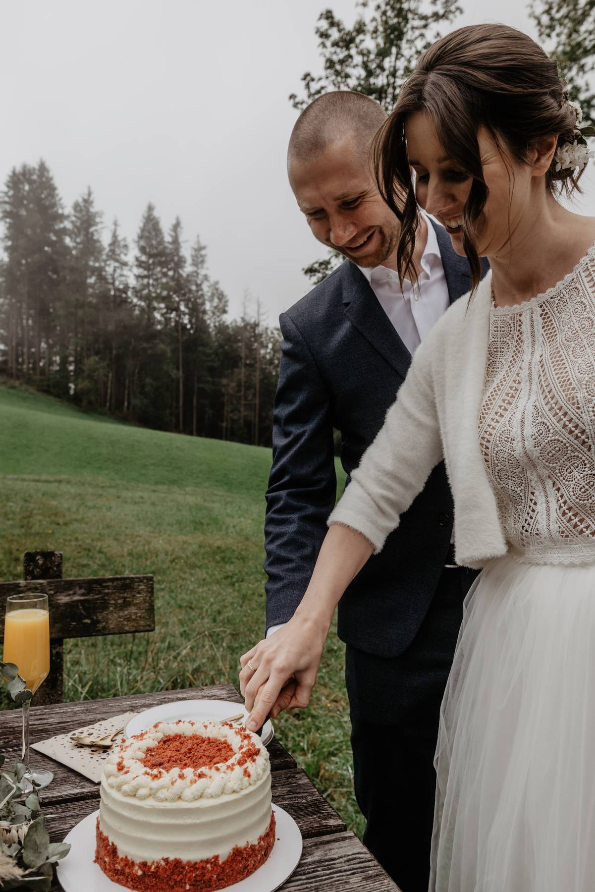 Couple cutting their wedding cake at a wooden bench
