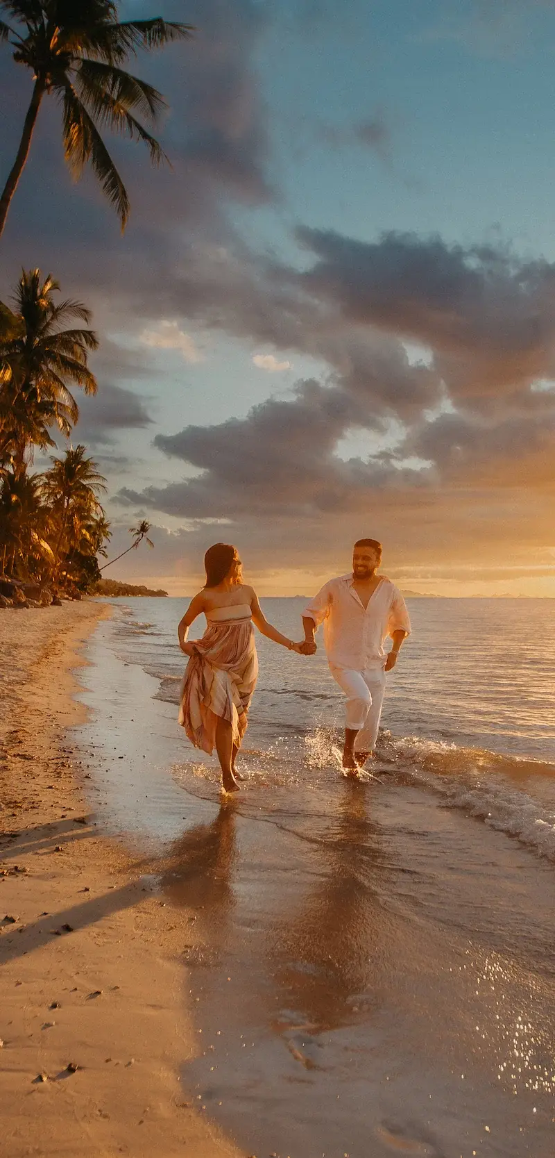 Smiling couple embracing on Bang Po Beach in Koh Samui as the sun sets over the water