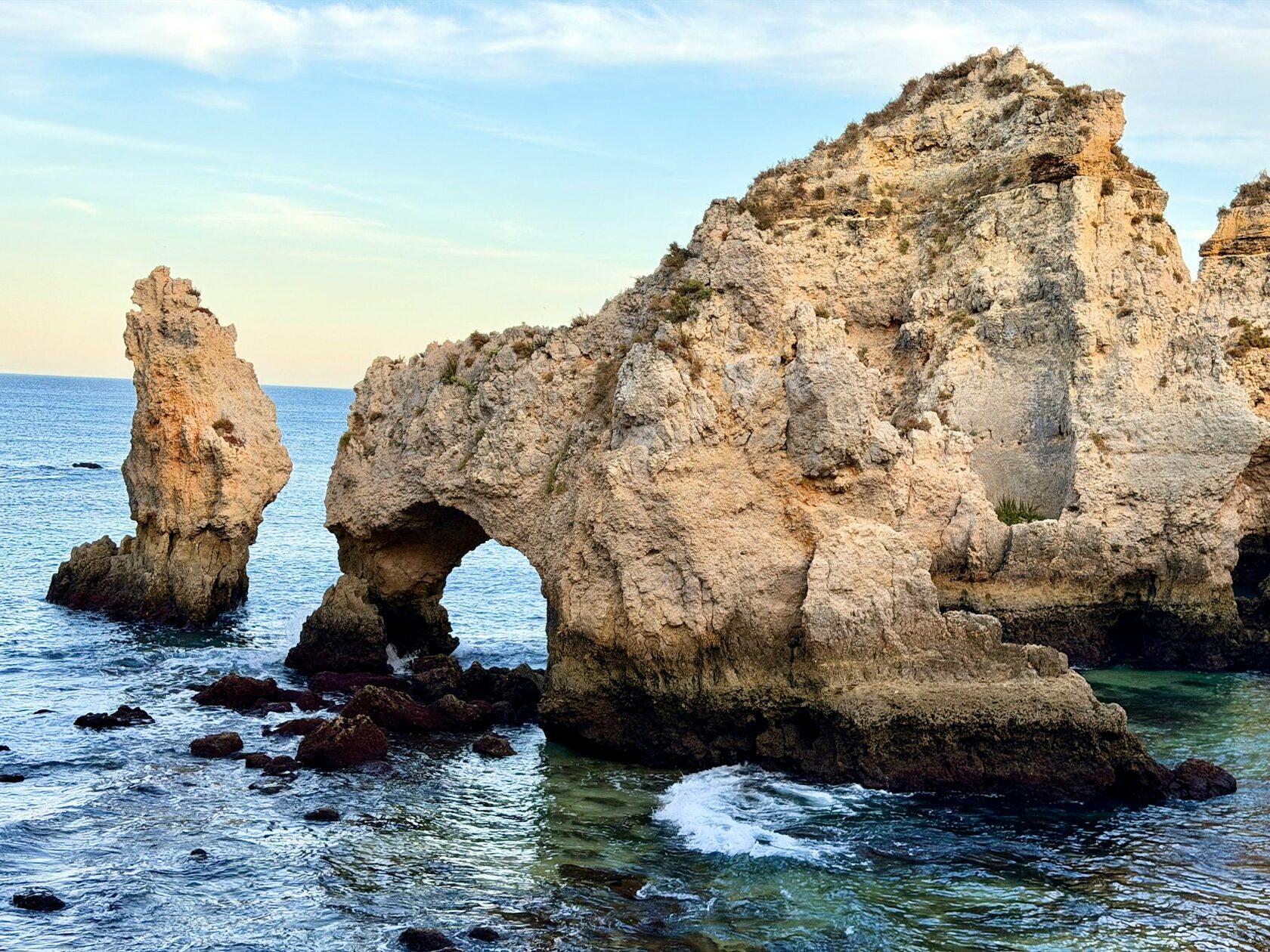 The golden rock arches of Ponta da Piedade rising from turquoise water, with a small boat passing between them
