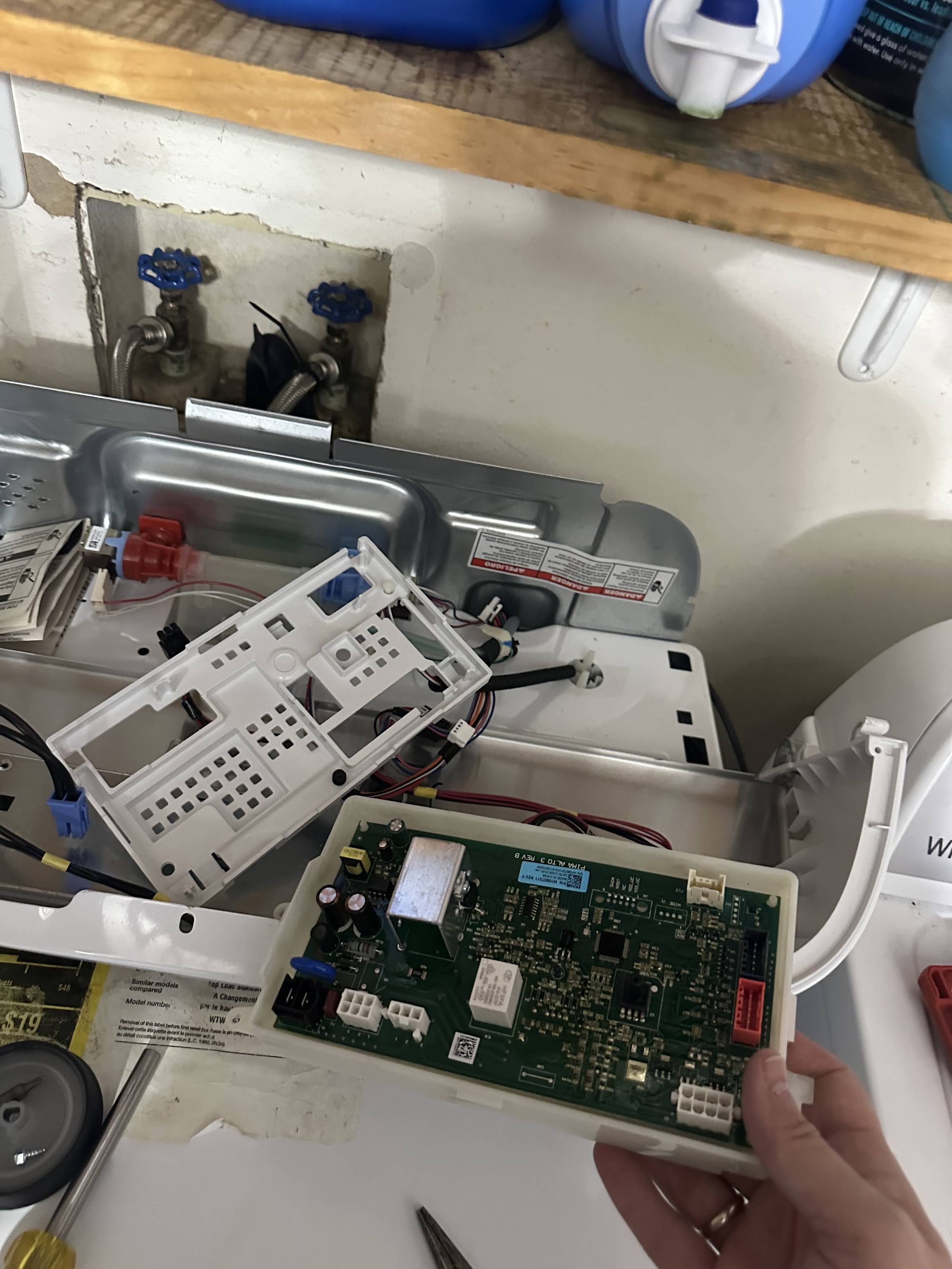 Technician holding a washing machine control board during an in-home washer repair by AVM Services