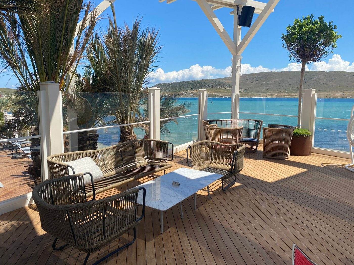 Seaside lounge terrace with glass wind protection and a view of the bay