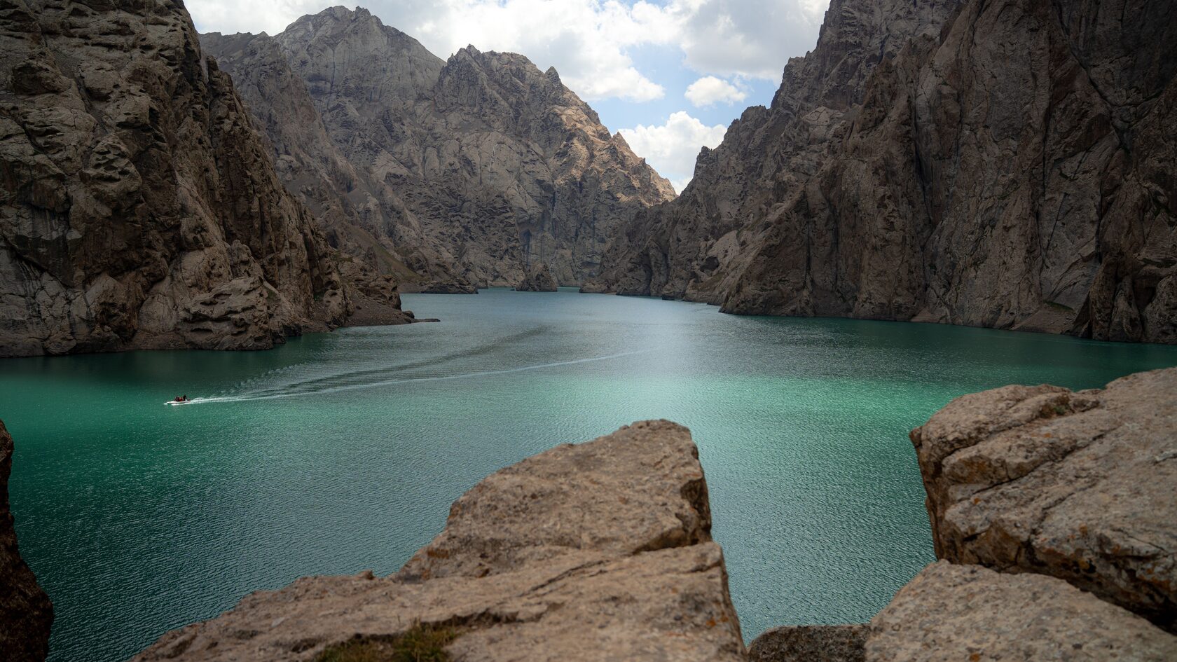 Turquoise Kel-Suu Lake beneath towering cliffs and mountain walls
