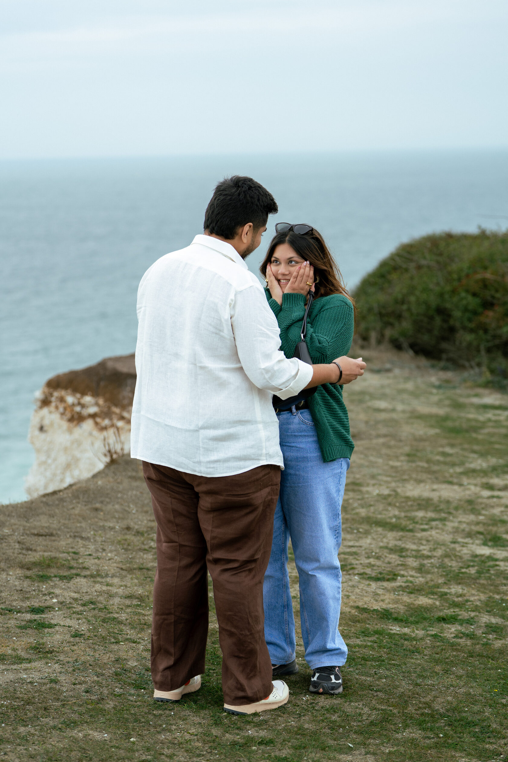 Couple reacting during a coastal marriage proposal at Seven Sisters