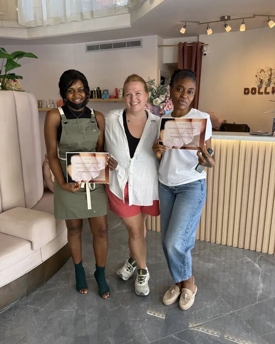 Two graduates holding their certificates, standing with Nina Georgi in the academy