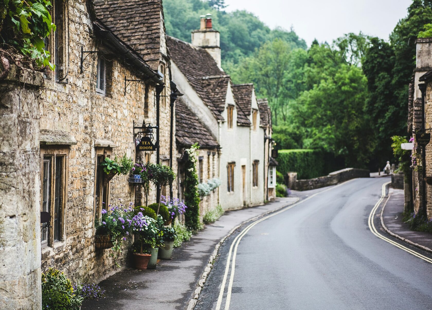 Arlington Row in Bibury, honey-colored stone cottages beside a stream in the Cotswolds, soft summer light