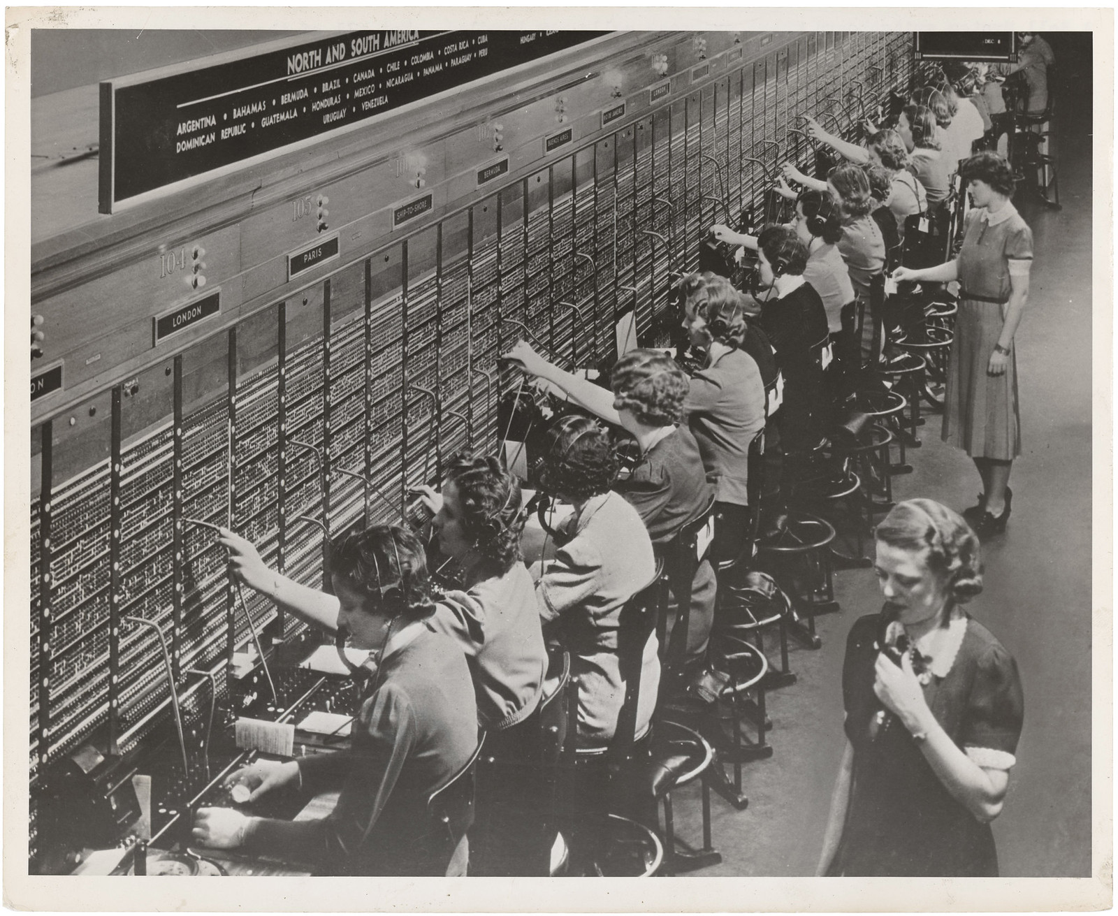 Archive photograph of women operators connecting calls at a long Bell System telephone switchboard