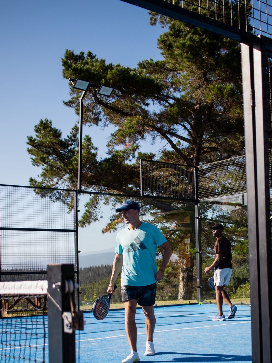Two players on an outdoor padel court on a sunny day