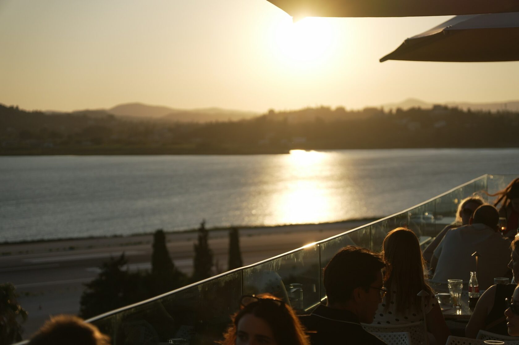 A couple raising glasses of wine on a terrace above a golden Algarve cove at sunset