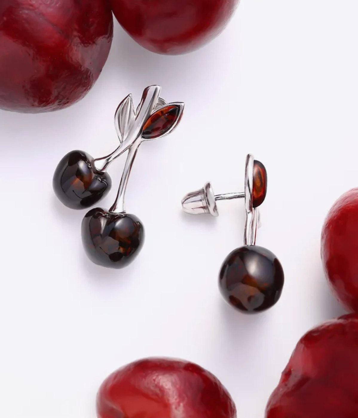 Cherry amber earrings on a plate of cherries