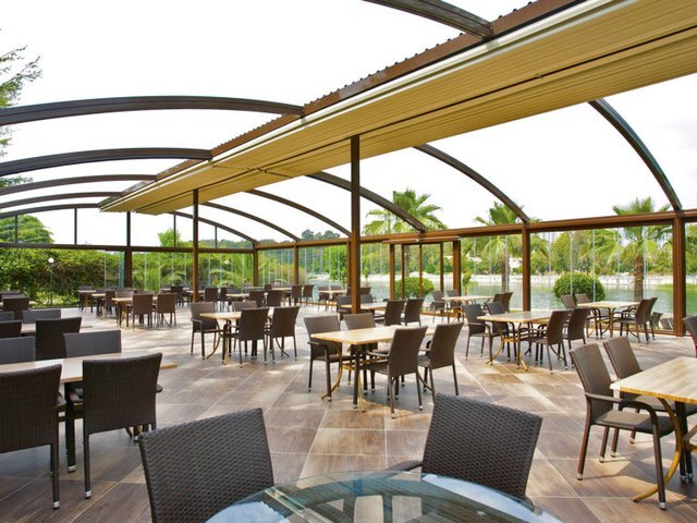VISTA curved awning pergola over a restaurant terrace with palm trees