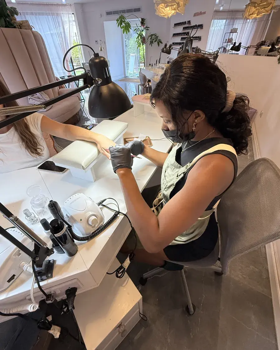 A student working with an e-file at a fully equipped nail workstation in the academy training room