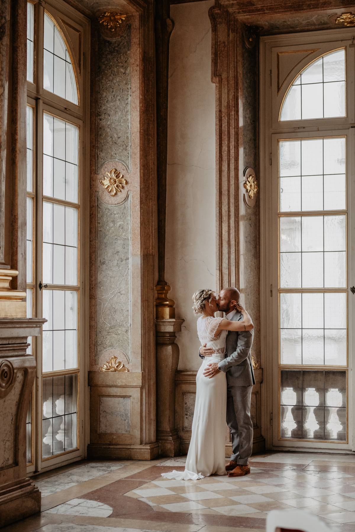 Bride and Groom sharing a kiss inside the elegant Marble Hall at Schloss Mirabell in Salzburg.