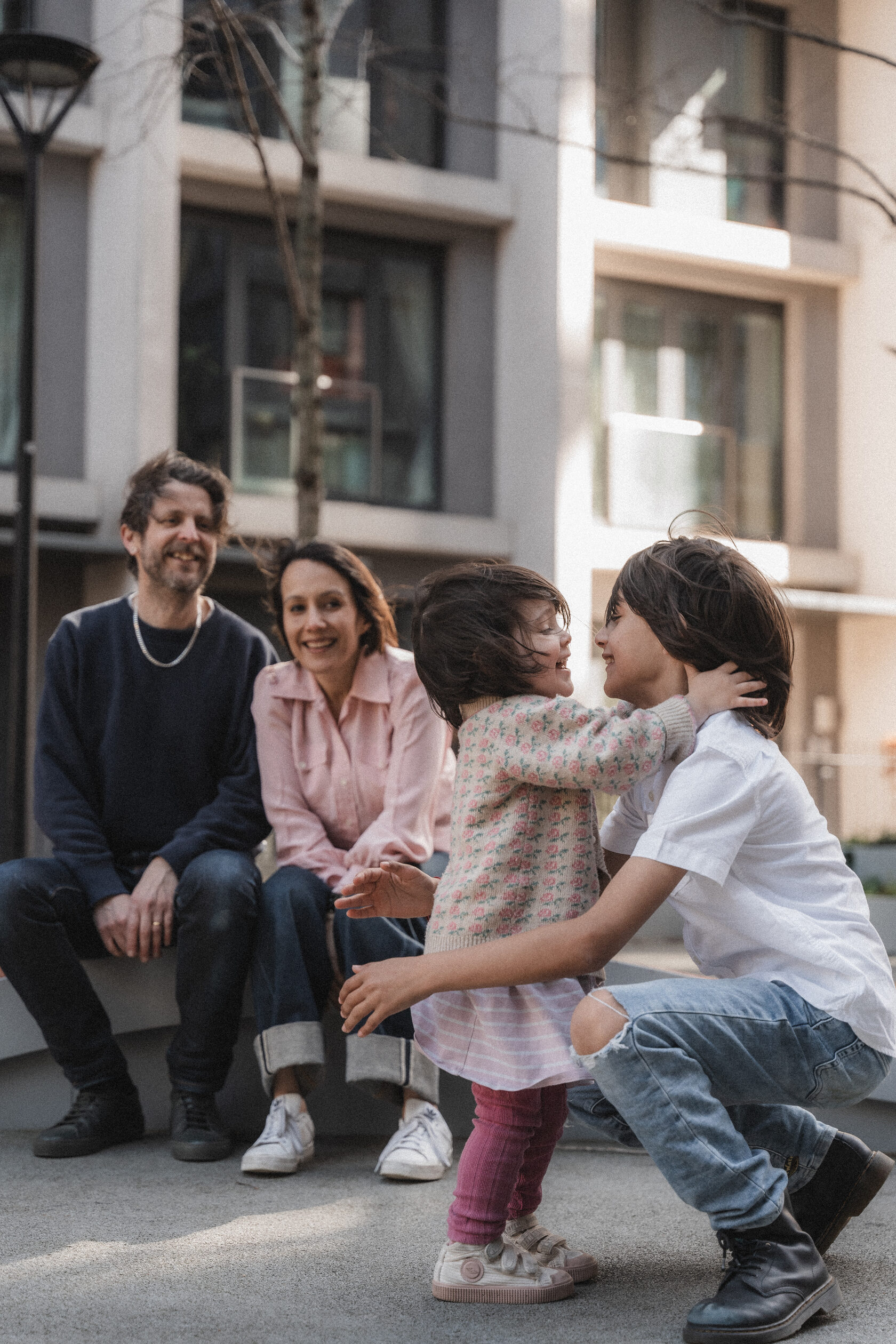 Parents and children sharing a playful moment on a city street