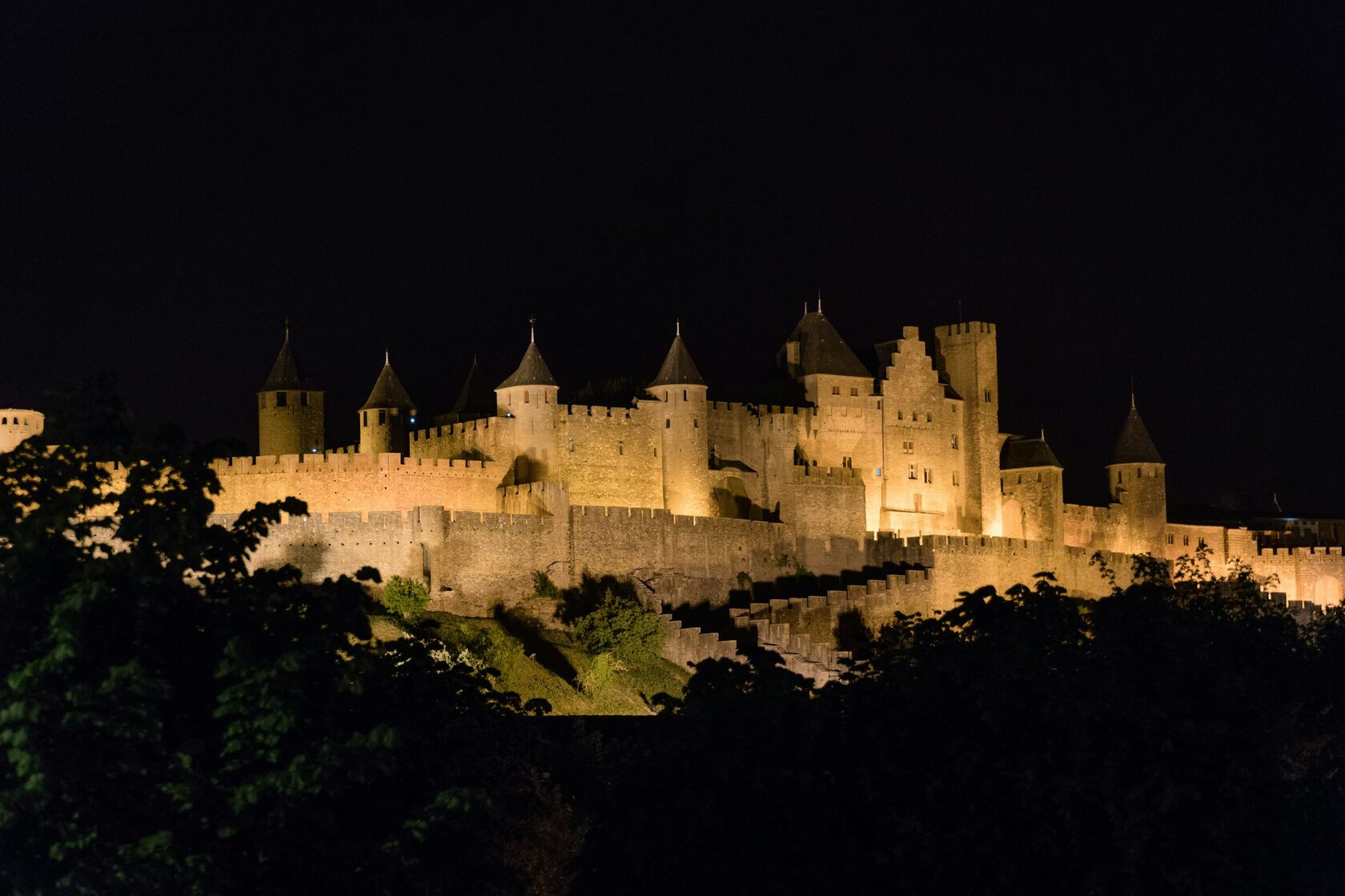The walled Cité of Carcassonne lit up at night with its towers and ramparts glowing gold