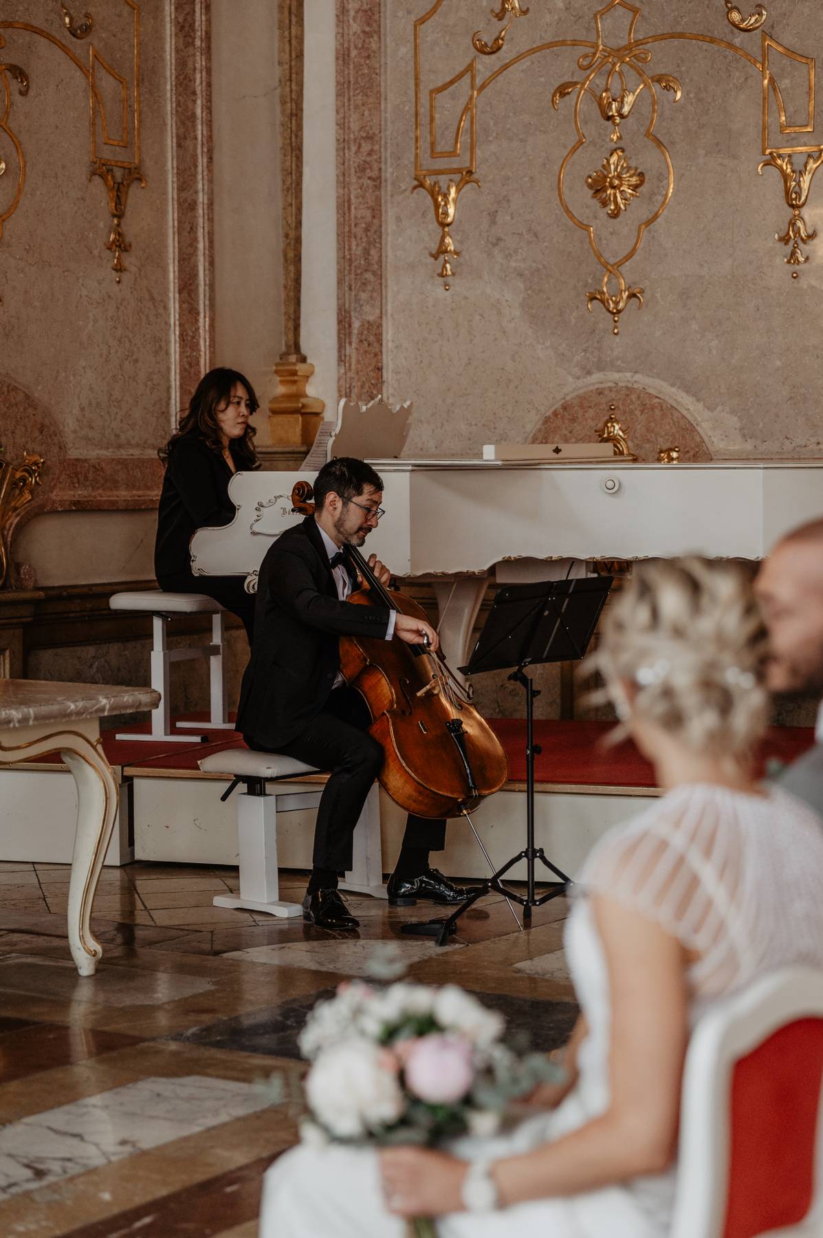 Cellist and pianist performing live music during intimate wedding ceremony at Schloss Mirabell.