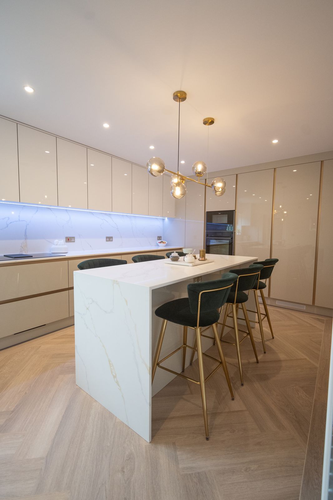 Waterfall marble-effect island with gold pendant light and tall handleless gloss units