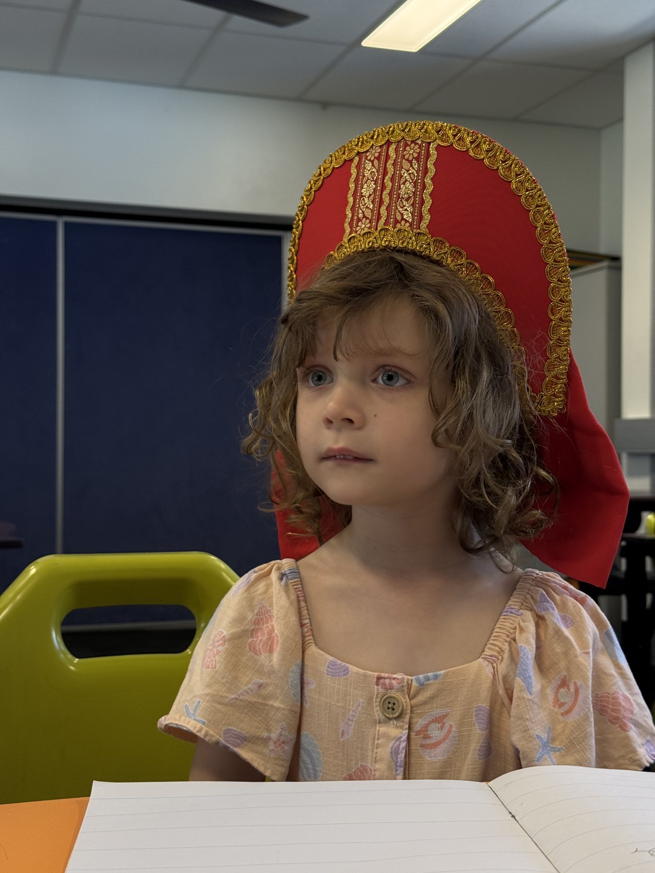 A girl in a red kokoshnik at her desk
