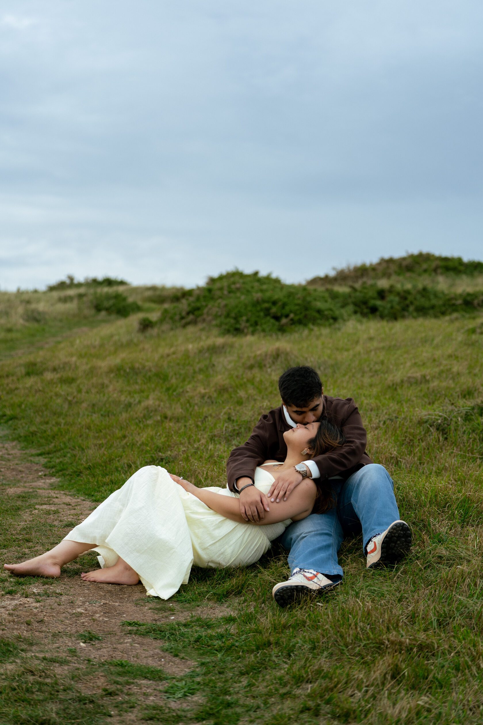 Relaxed couple portrait lying and sitting on coastal grass