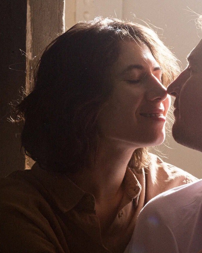 A couple about to kiss in warm window light