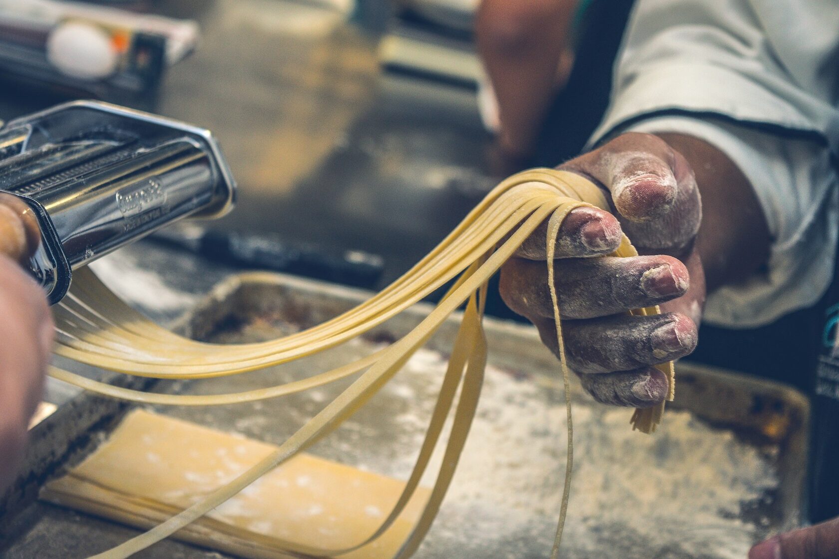Hands shaping fresh pasta on a wooden board
