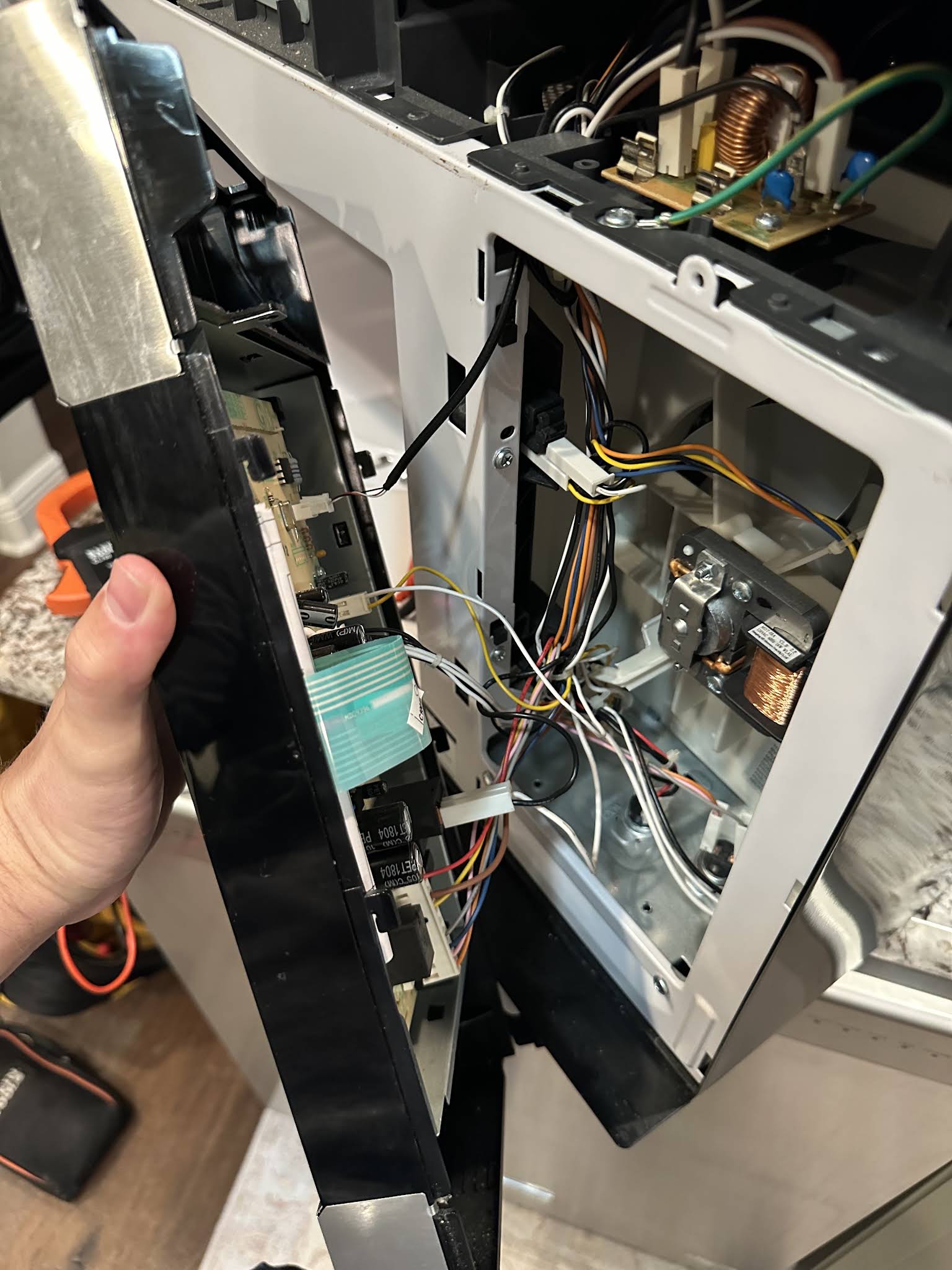 Over-the-range microwave opened with the control panel and wiring exposed during an AVM Services repair