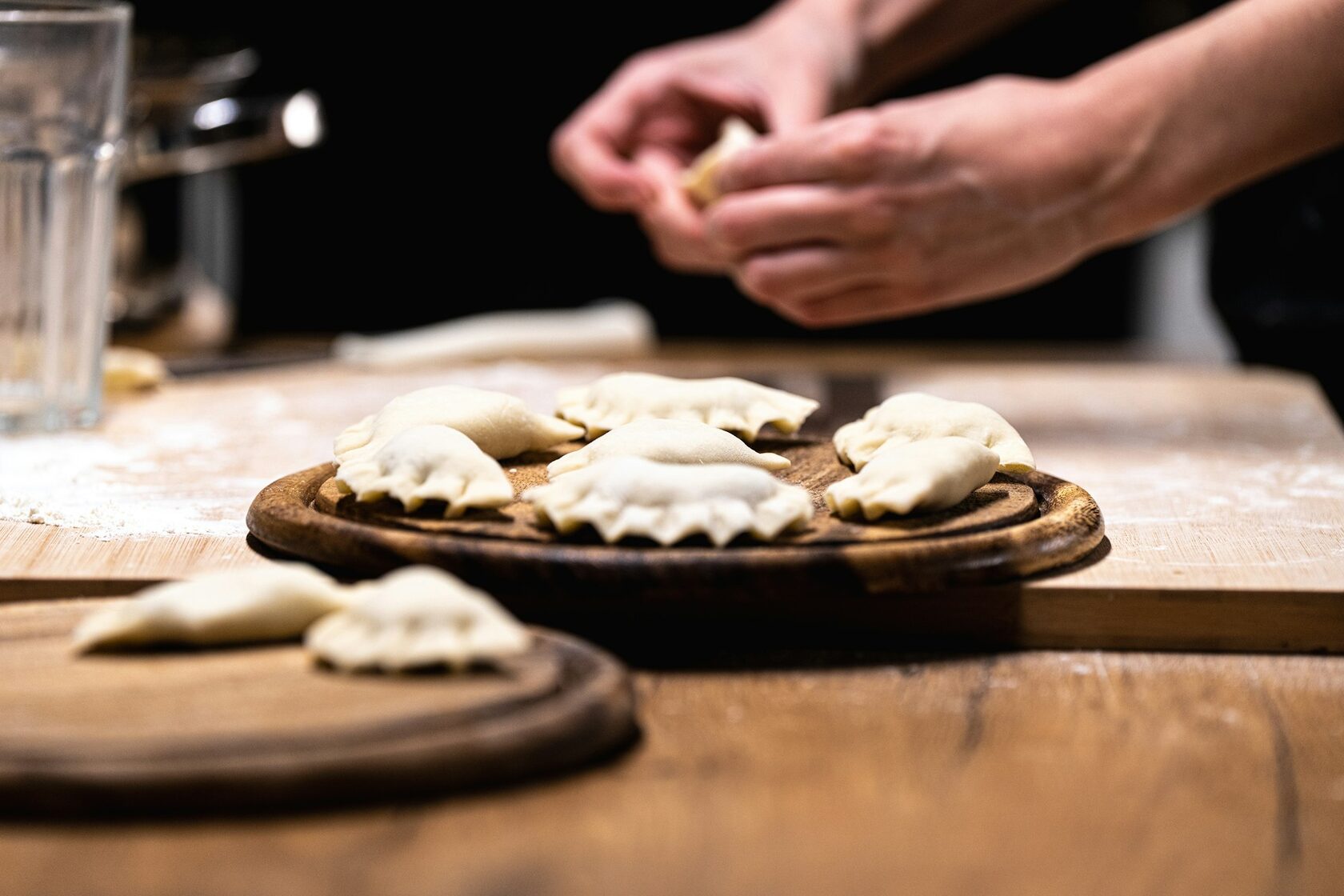 Hands shaping fresh pasta on a wooden board