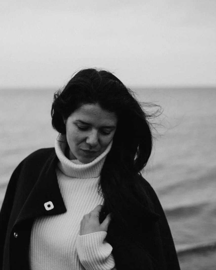 Black and white portrait of a woman in a white jumper by the sea