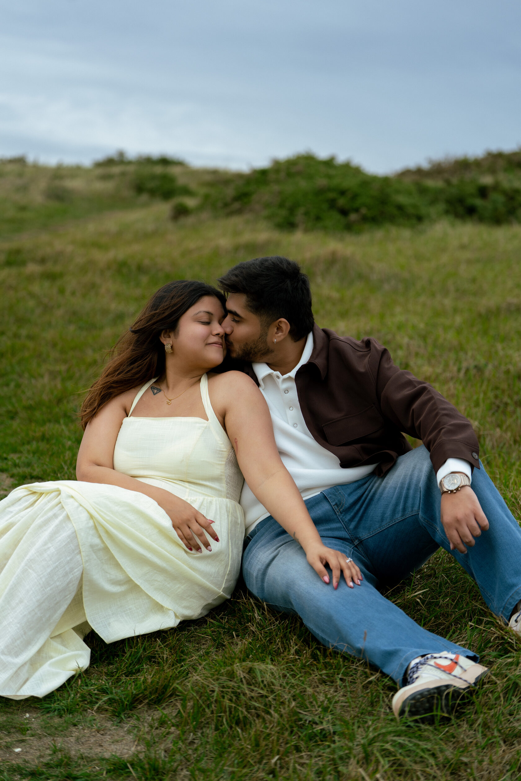 Couple sitting close together on a grassy slope