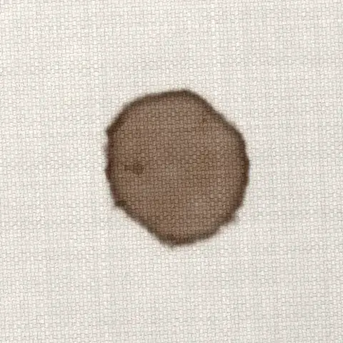 Symbolbild: eingetrockneter Schokoladenfleck auf hellem Sofastoff in Nahaufnahme. Solche Flecken bekommt Shikardos Reinigung in Bad Homburg in der Regel gut heraus.