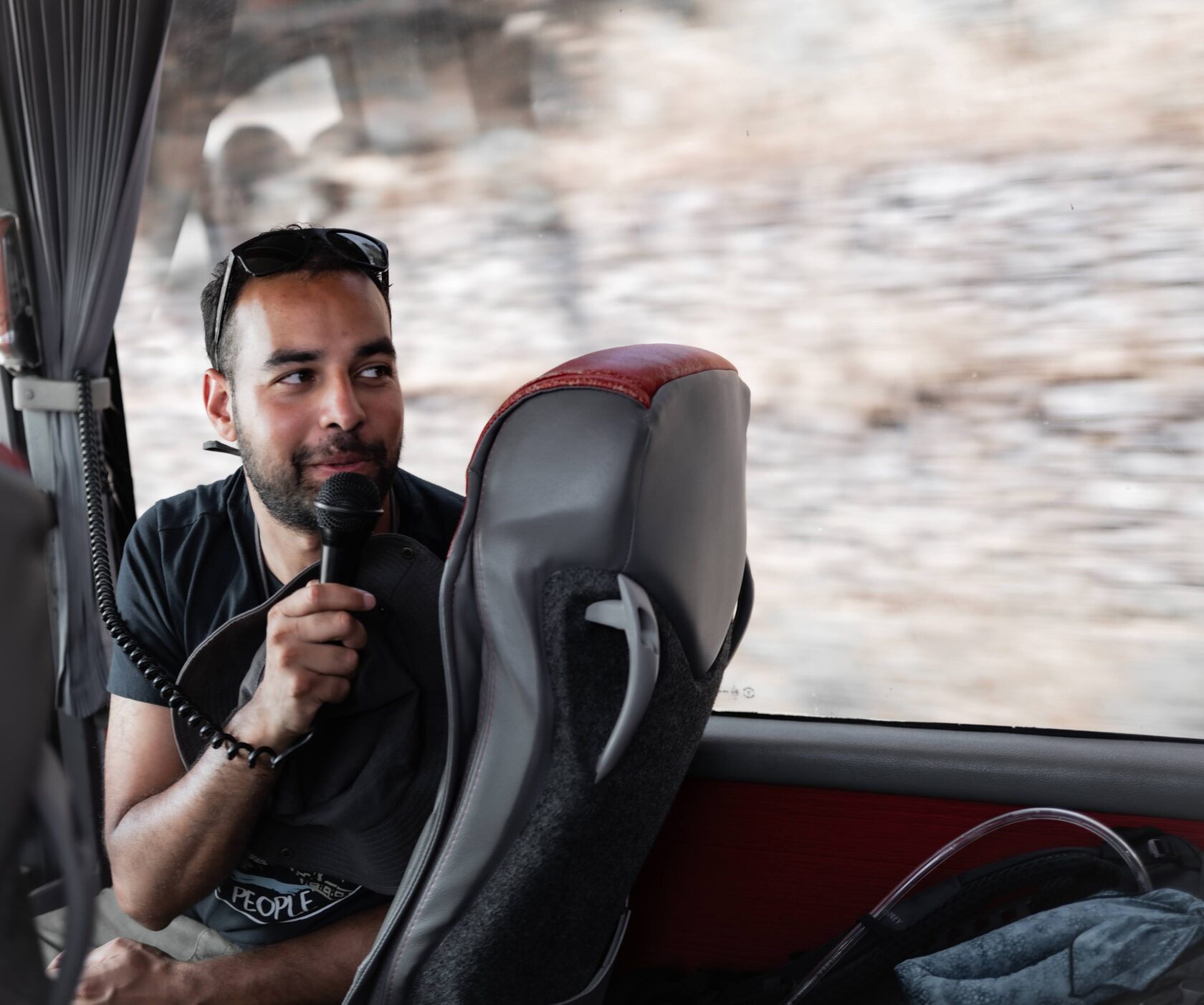 A Tour Director speaking with guests aboard a coach on the road