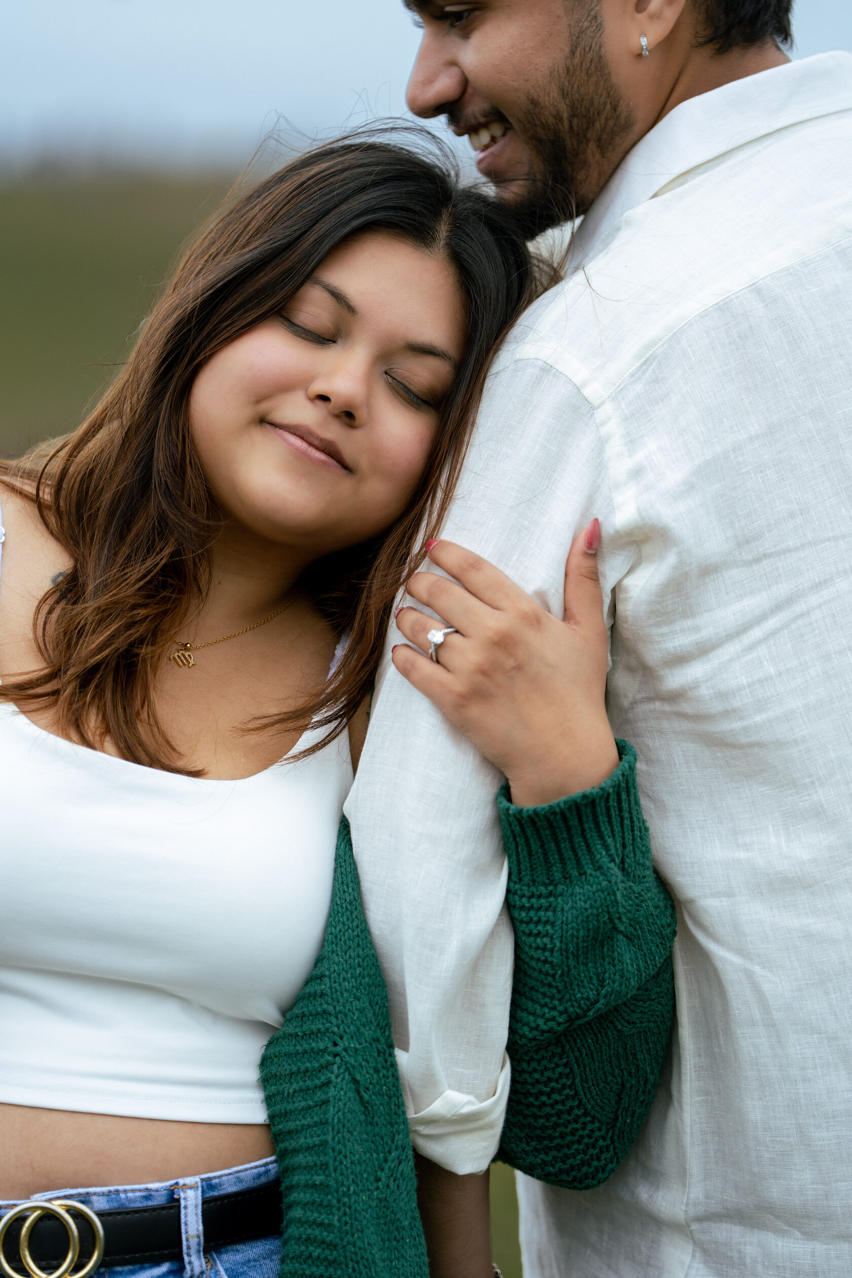 Close-up of an engagement ring as a couple embrace