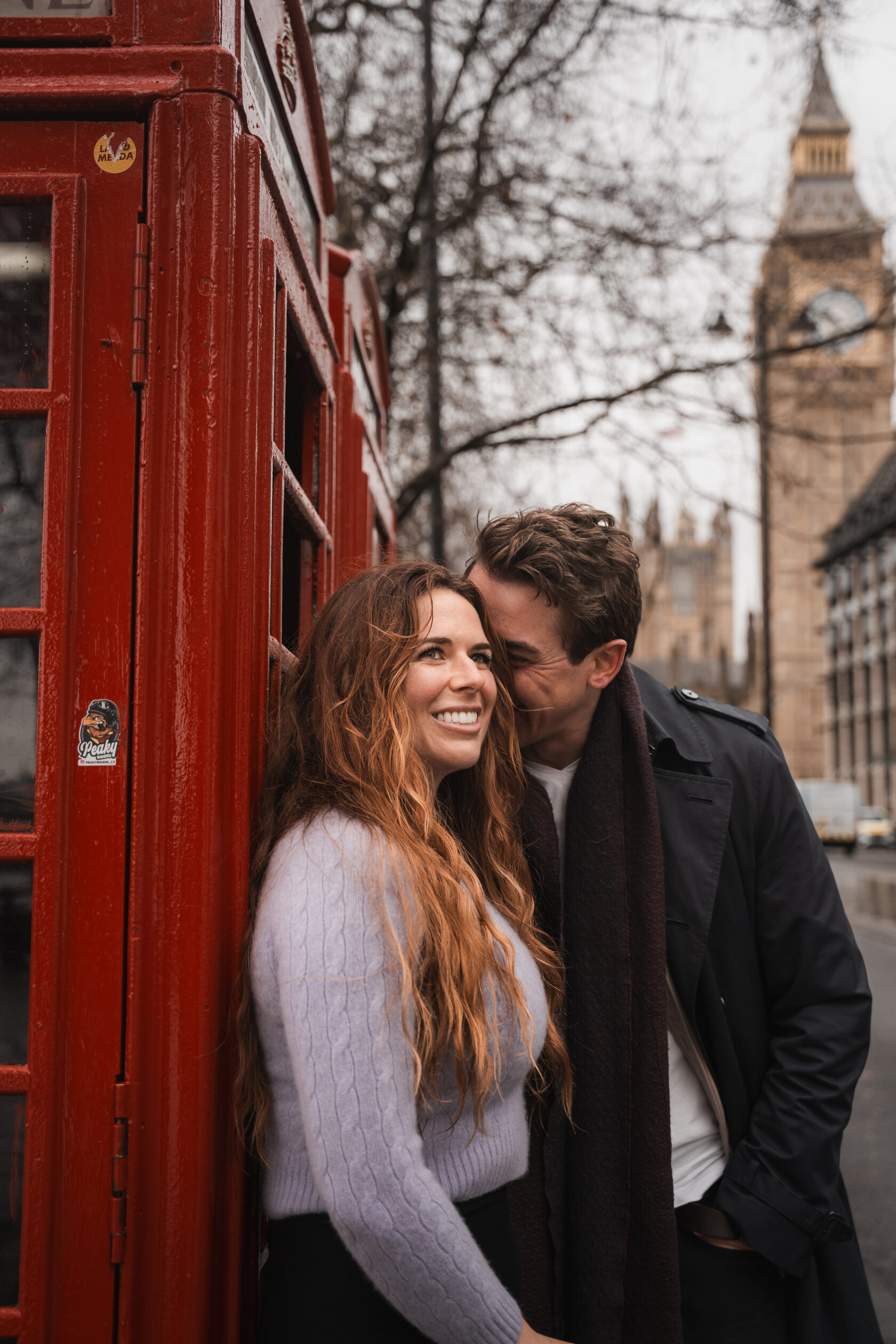 A smiling couple beside a red telephone box with Big Ben behind them
