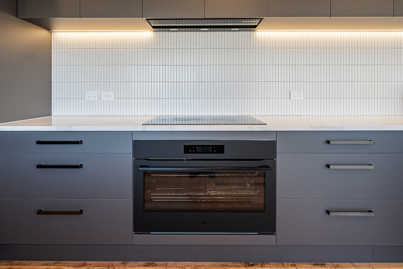 Built-in oven, dark drawers and vertically tiled splashback in the renovated Glenfield kitchen