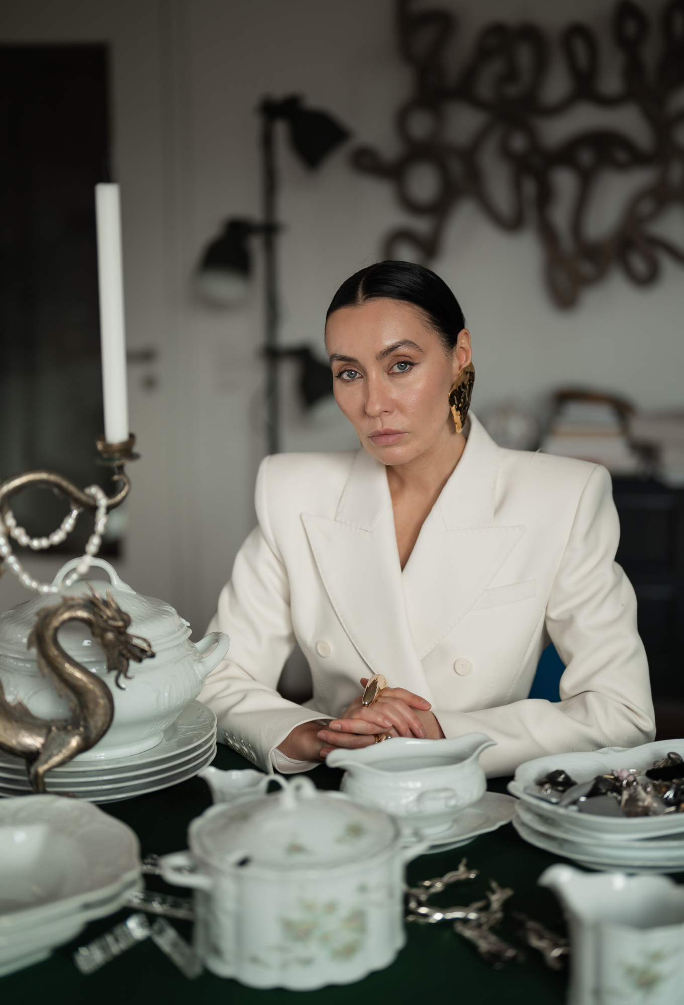 Personal-Branding-Portrait einer Frau im weißen Blazer an einem Tisch mit Porzellan und Vintage-Objekten