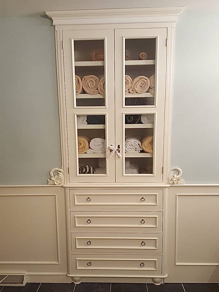 Bathroom built-in storage cabinet with lower drawers and decorative carved floral motif 