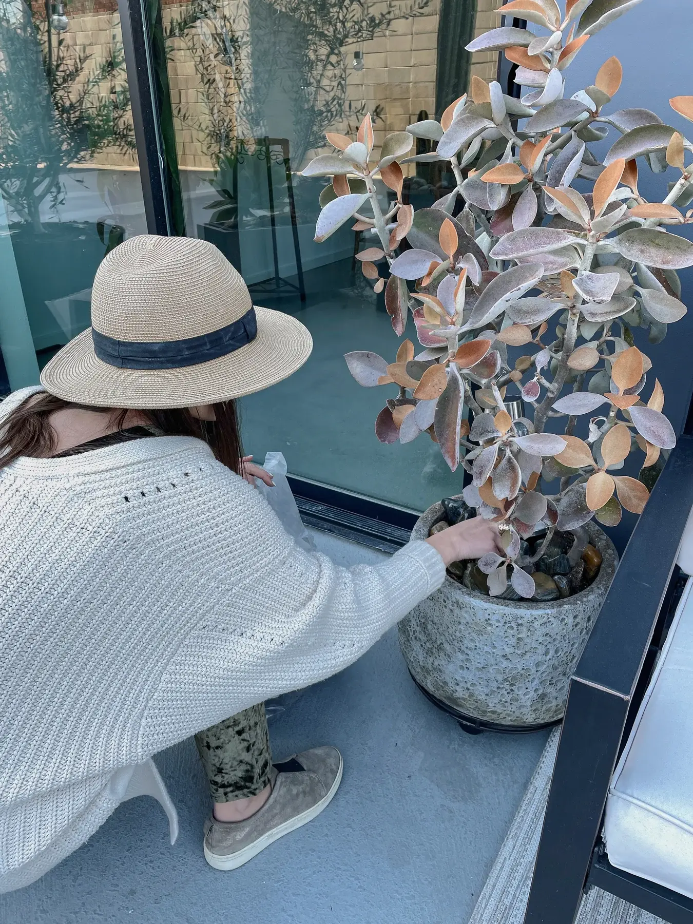 Katya Gustova in a sun hat tending a potted kalanchoe on a patio in Solana Beach