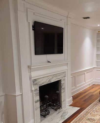 Living room fireplace with historic paneling and built-in shelves.