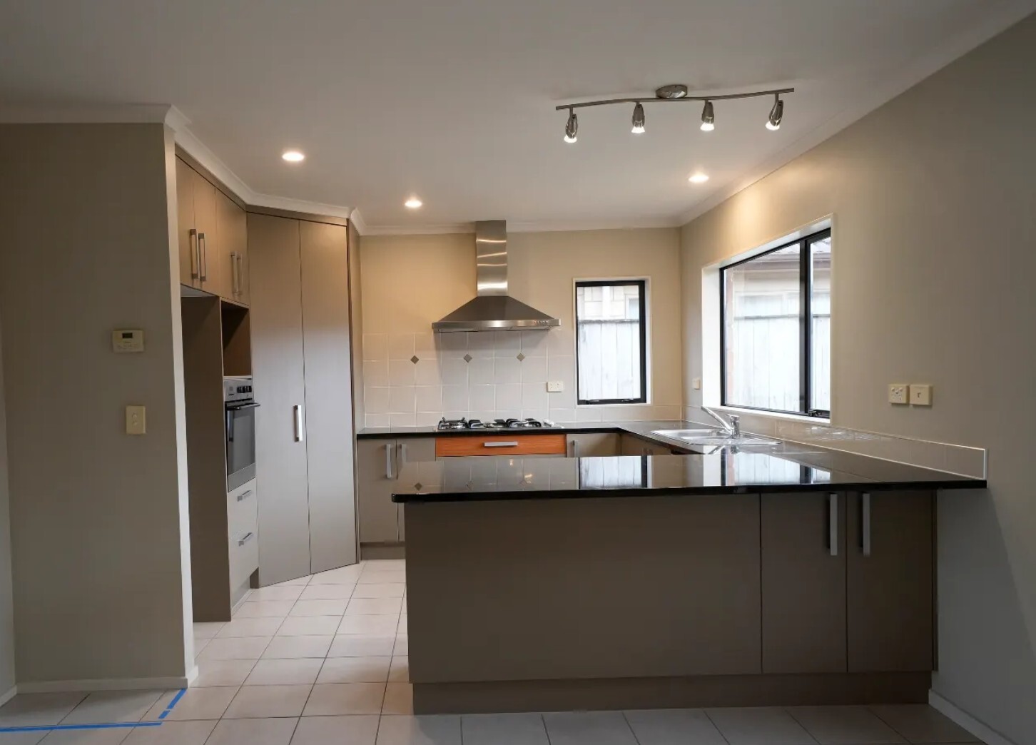 Before: Original Flat Bush kitchen with beige cabinetry, black peninsula benchtop and stainless steel rangehood